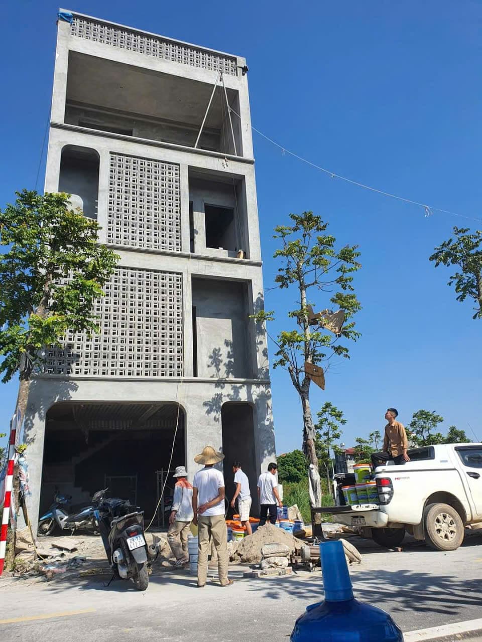 Nhà phố khung bê tông với hệ tường hoa che nắng, thợ đang làm việc trước mặt tiền.